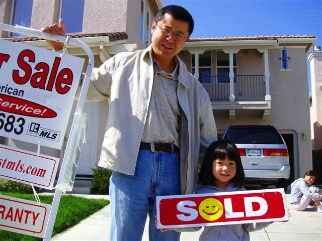 Photo of 1 of our Sellers with a Sold sign in front of their home.