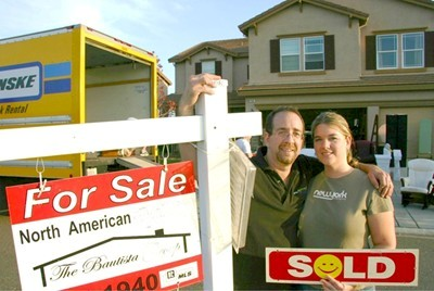 Photo of 1 of our Sellers with a Sold sign in front of their home.