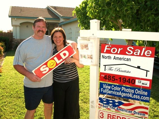 Photo of 1 of our Sellers with a Sold sign in front of their home.